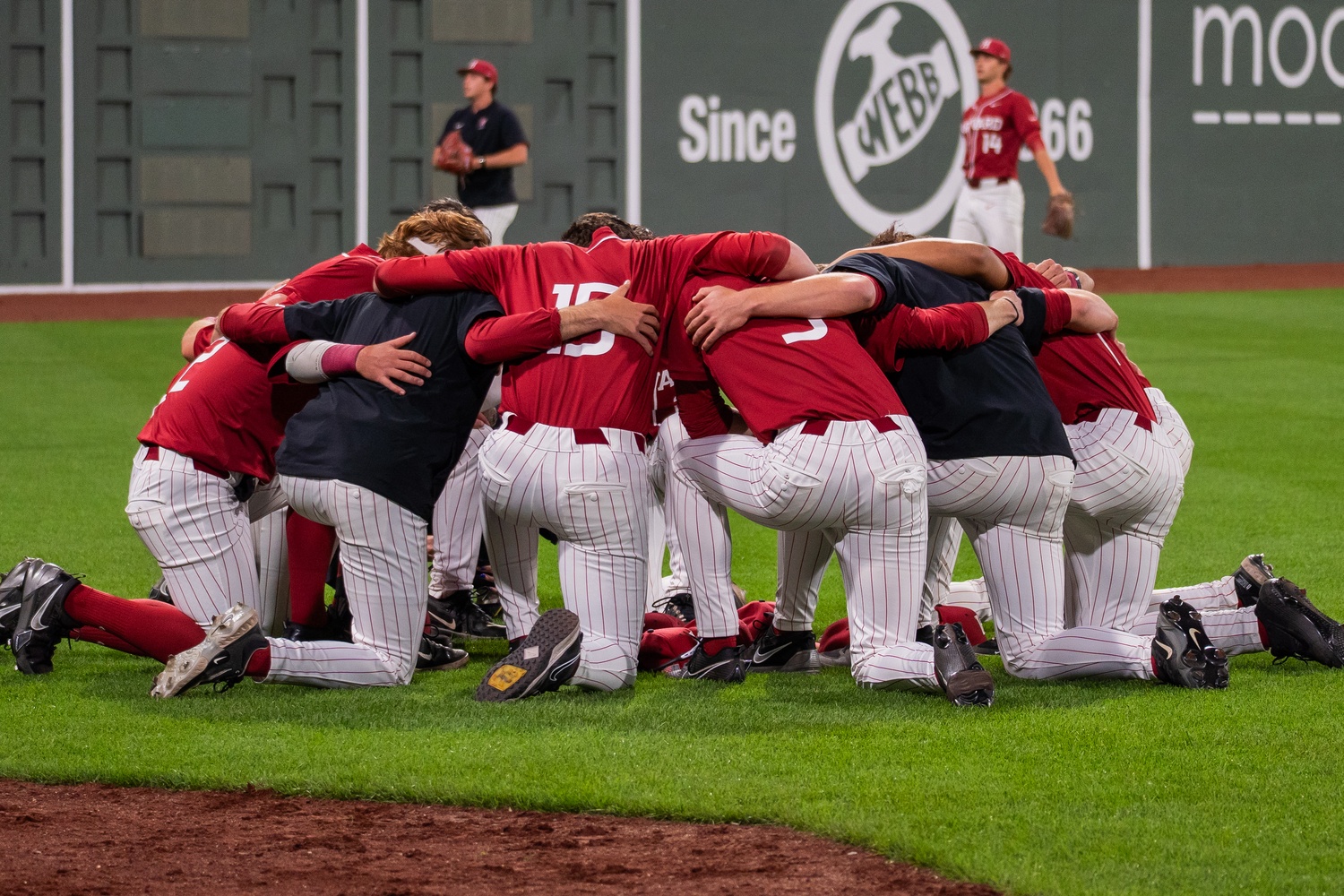 Harvard players gather on the field of Fenway Park ahead of the first pitch of the 2025 Baseball Beanpot championship final. The Crimson fell to Northeastern 5-4 in the tournament’s first return to Fenway since 2019.