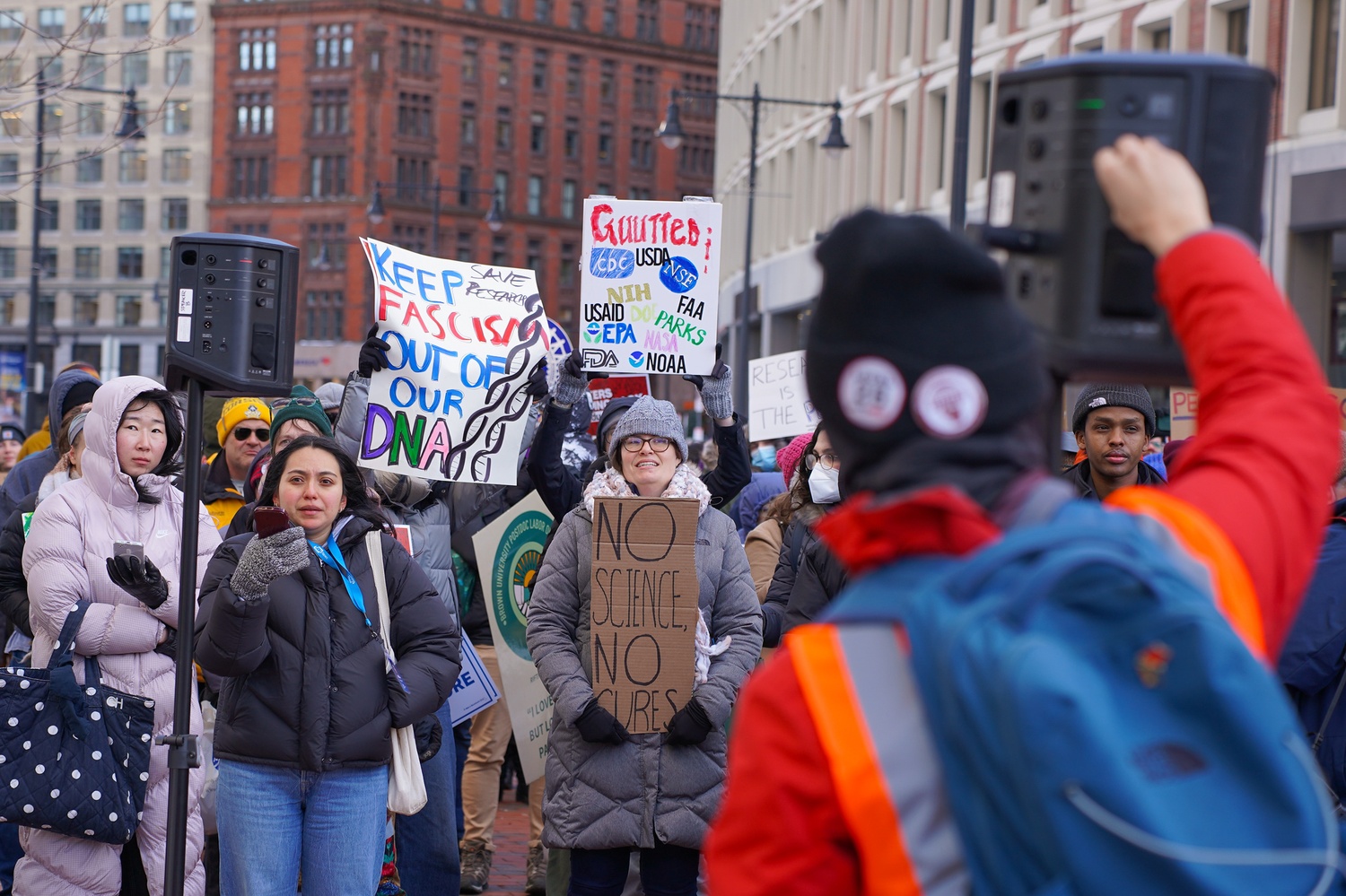 A protester raises their fist during a rally outside the John F. Kennedy Federal Building in Boston against President Donald Trump’s proposed cuts to federal research funding. More than 300 researchers, educators, and students participated in the protest.