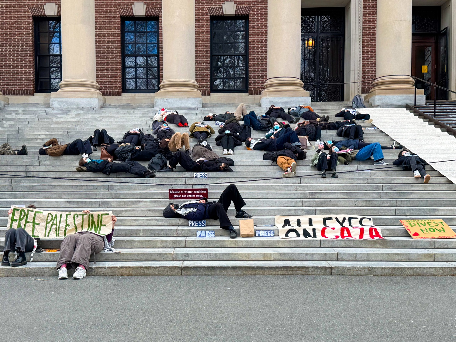Students lie on the steps of Widener Library during a “die-in” protest organized by Harvard Out of Occupied Palestine against the war in Gaza. More than 60 participants wore masks and remained silent for 17 minutes as the names of Palestinians killed in the conflict were read aloud.