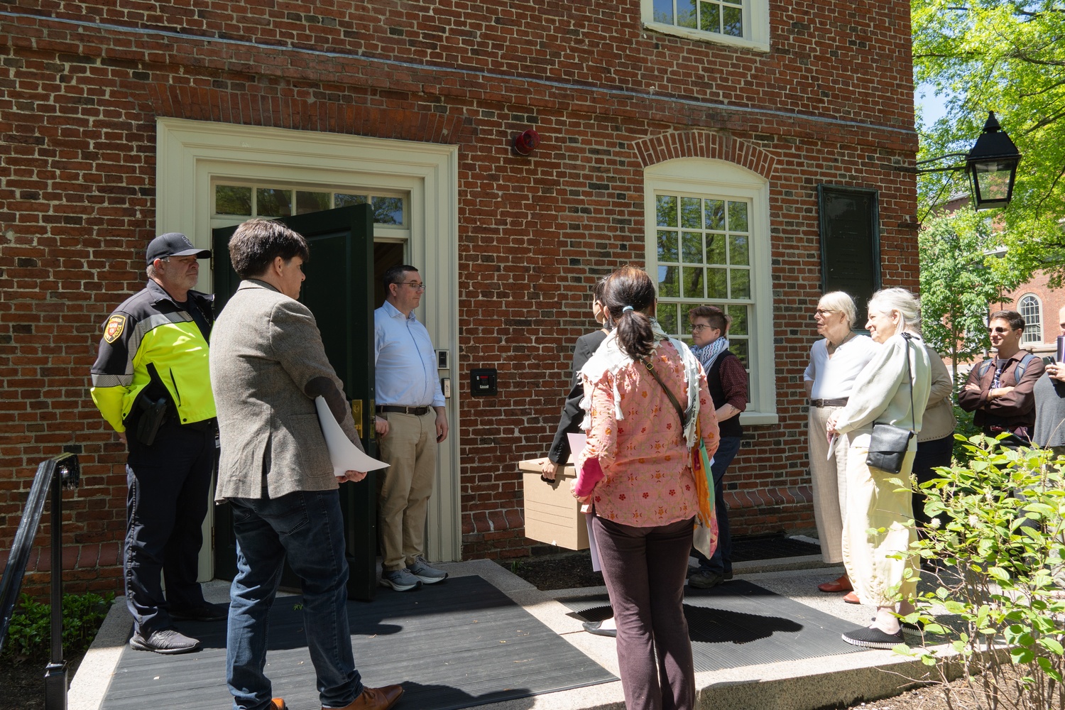 Harvard affiliates deliver a box containing 452 discrimination complaints to a University employee outside Massachusetts Hall during a rally alleging anti-Muslim, anti-Arab, and anti-Palestinian bias on campus. Organizers said the University had ignored prior submissions to the Office for Community Conduct and demanded stronger protections for affected students.