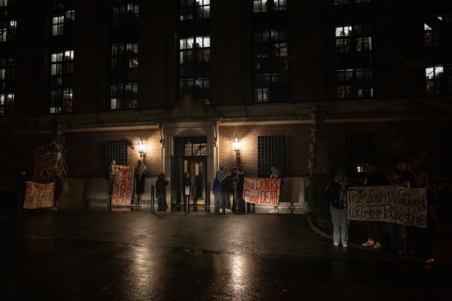 Protesters hold signs reading “40,000 Gazans now are dead” and “Your donor $s fund death” outside the back entrance to Widener Library during a rally targeting Harvard donors attending the President’s Associates dinner. The demonstration called on the University to divest from companies linked to human rights abuses.